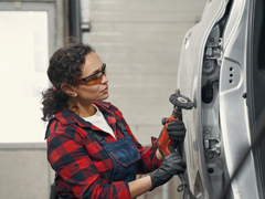 female with red plaid shirt doing autobody repair