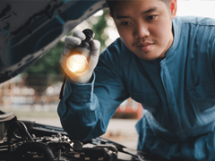 asian mechanic looking into engine bay